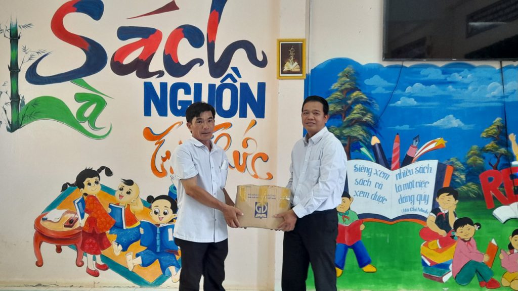 Ông: Nguyễn Tấn Công (bên phải) trao sách cho trường. Ông Đặng Văn Quang ( bên trái)đại diện nhà trường nhận.